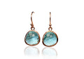 Pair of earrings with blue gemstones and gold-colored settings on a white background