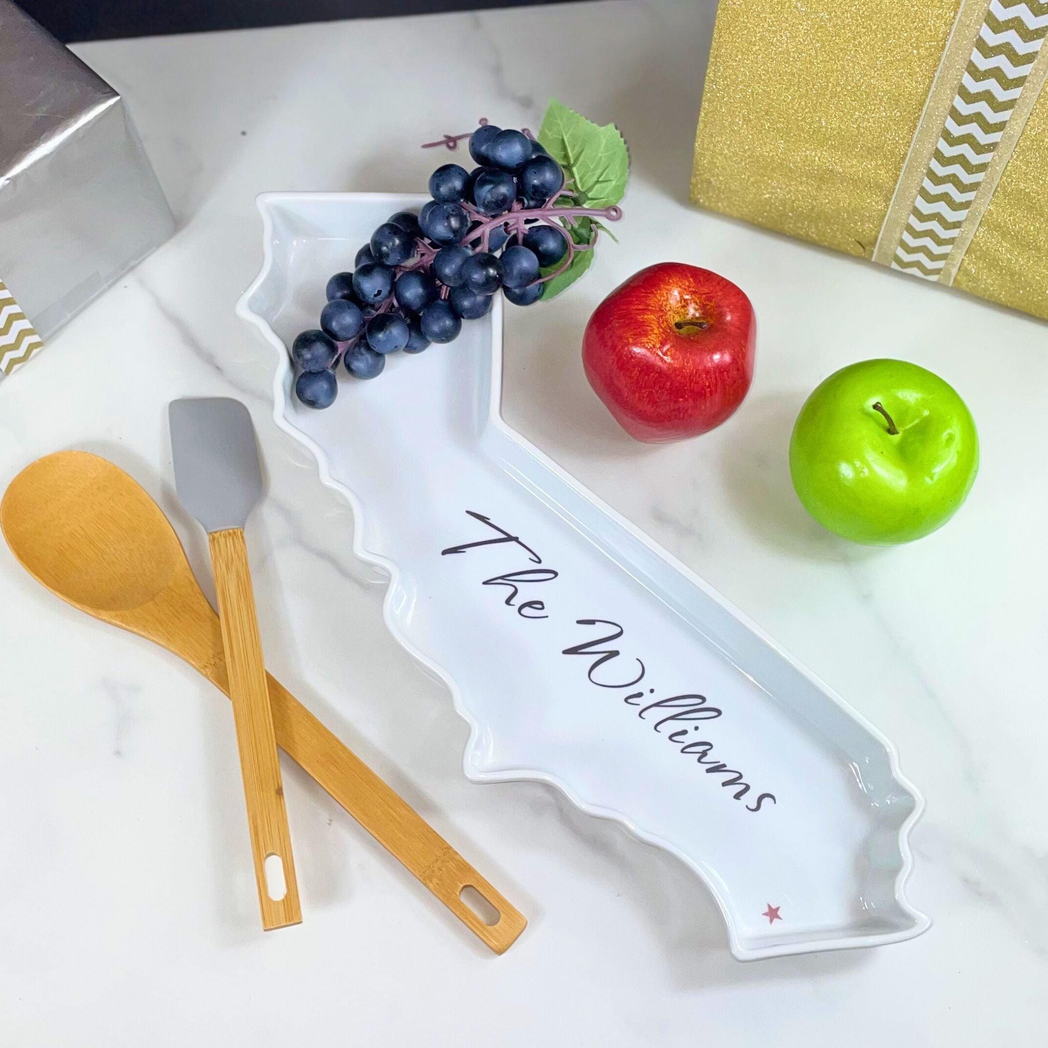 Personalized white serving dish shaped like California with fruits and utensils on a white surface