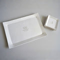 White rectangular tray with engraved initials and date on a gray background