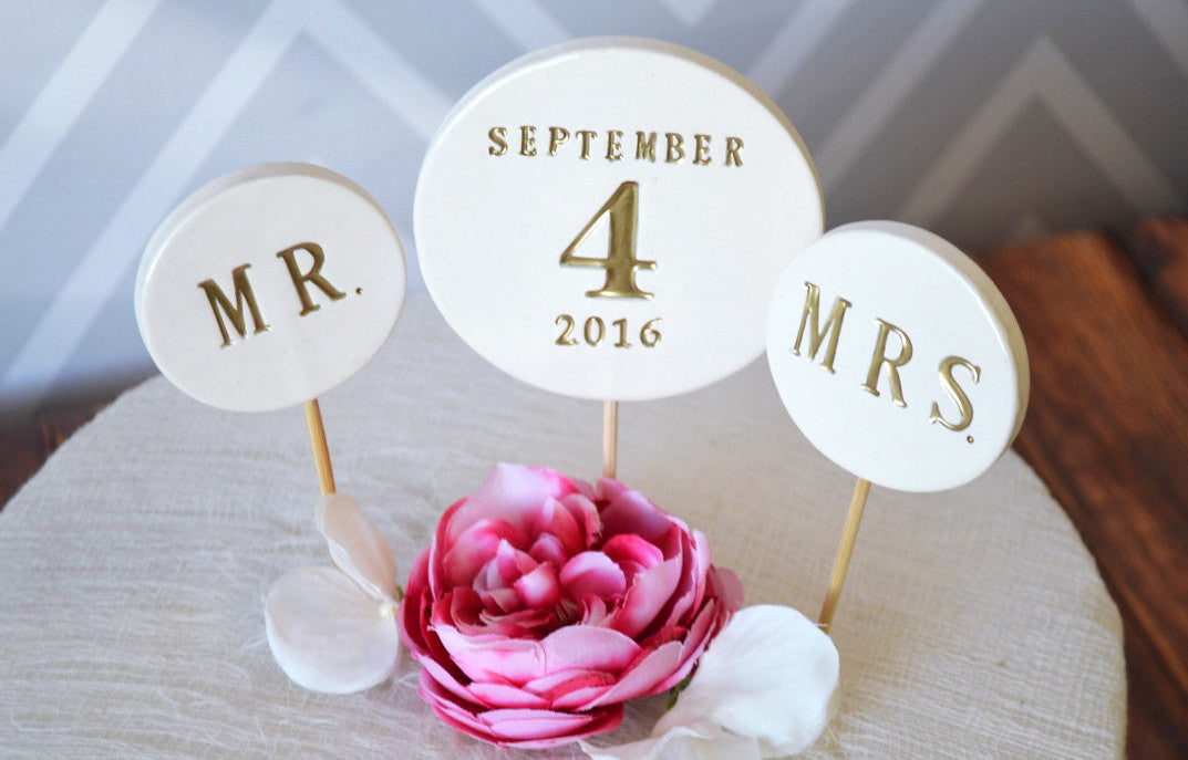 Wedding-themed cupcake toppers with 'MR.', 'SEPTEMBER 4 2016', and 'MRS.' text, accompanied by a pink flower.