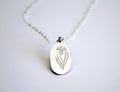 Silver pendant with floral design on a white background