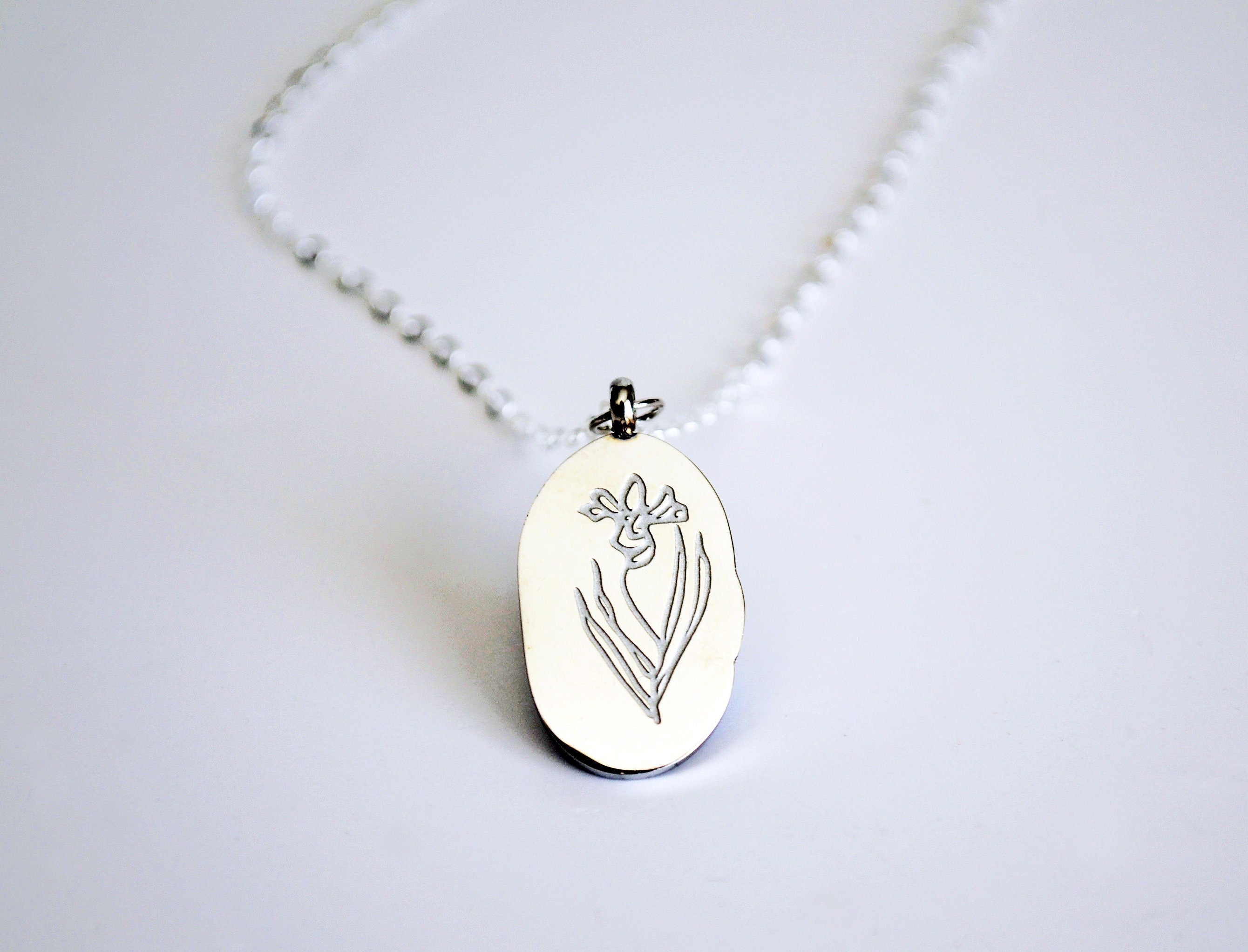 Silver pendant with floral design on a white background