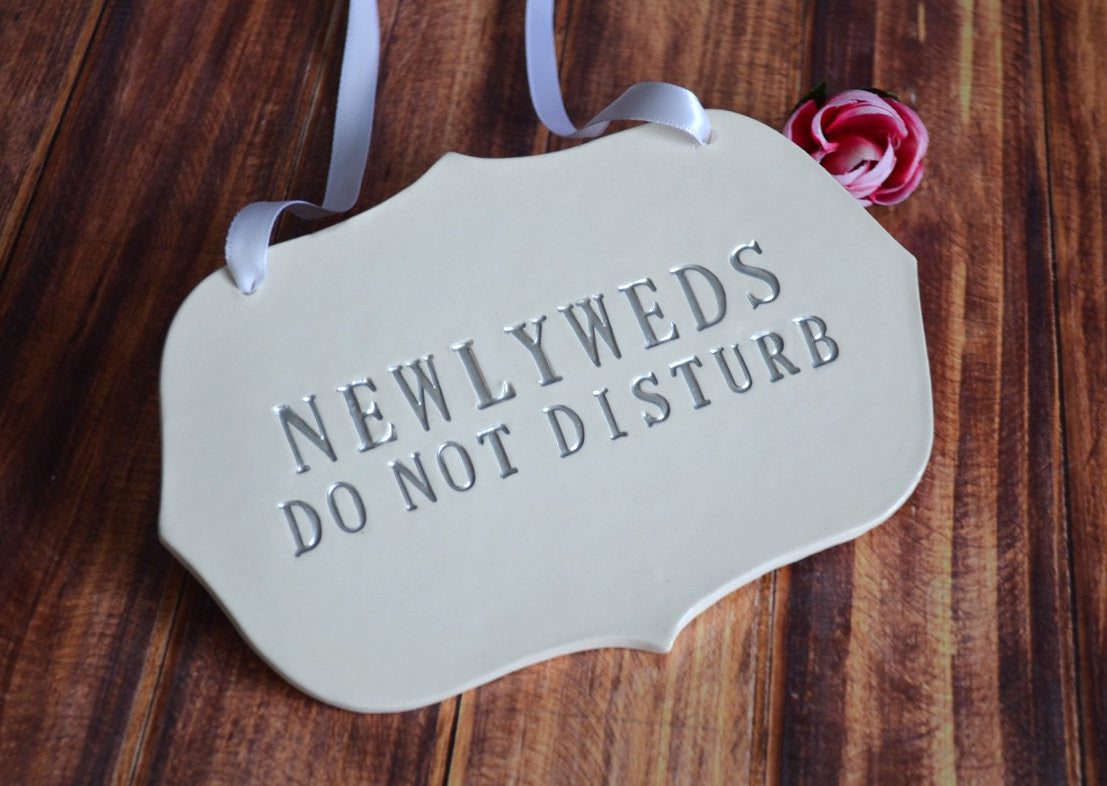 Decorative sign with 'NEWLYWEDS DO NOT DISTURB' text on a wooden background