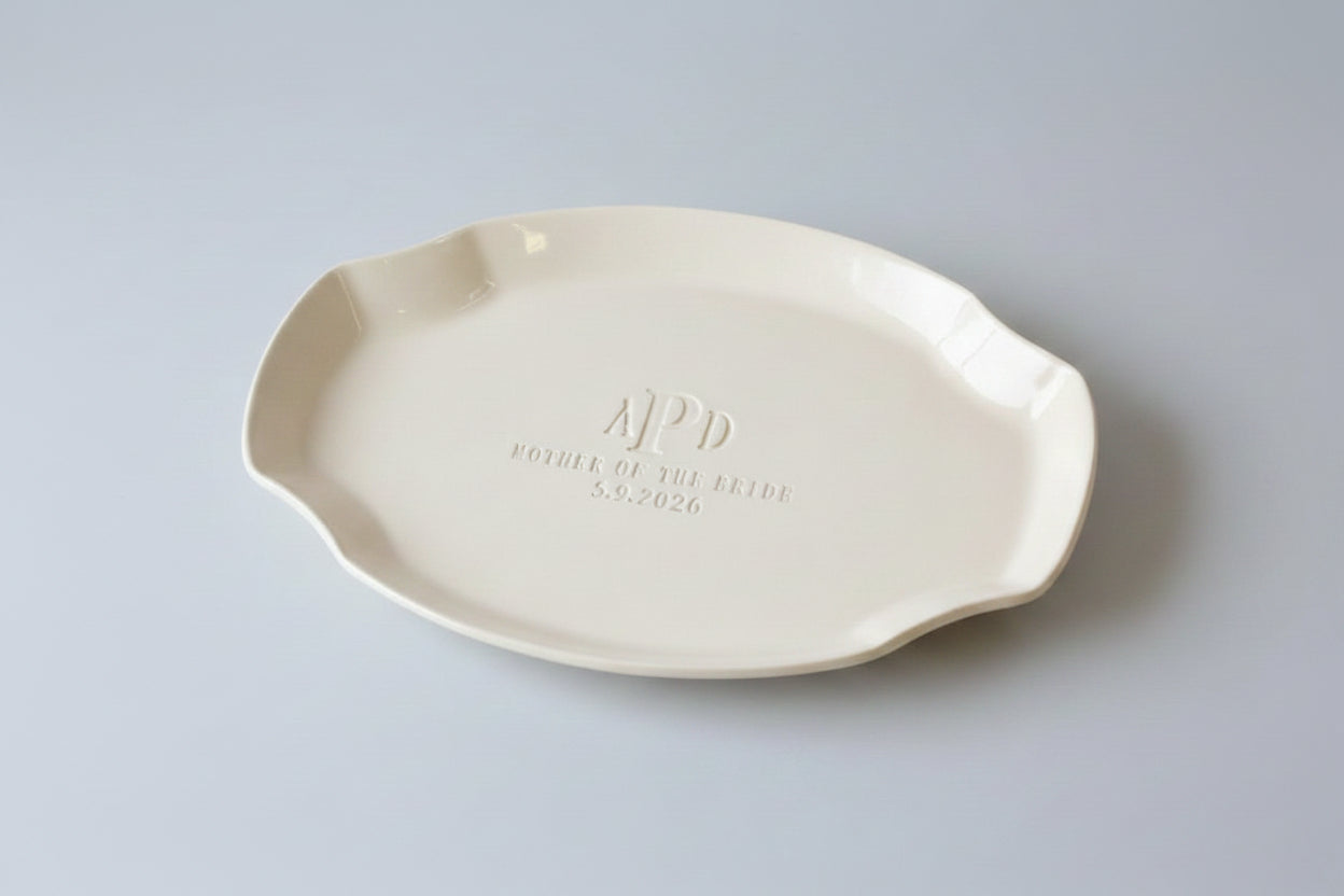 Ivory colored, handmade ceramic dish with 'APD' and Mother of the Bride with wedding date on a gray background