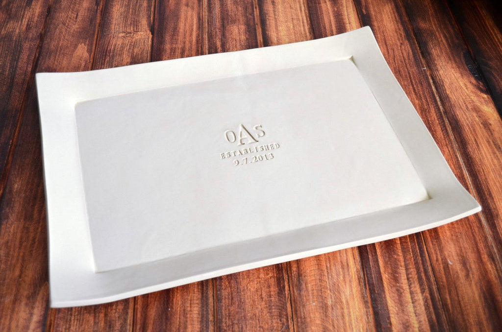 White ceramic tray with 'OAS' branding on a wooden surface