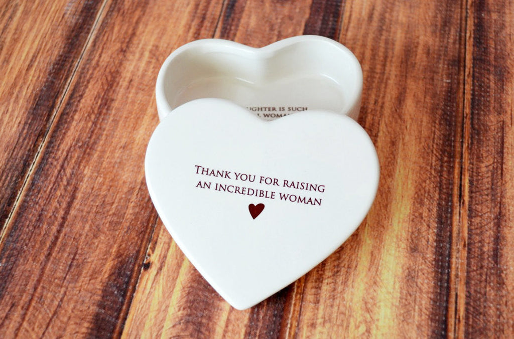 Heart-shaped white ceramic container with engraved text on a wooden surface